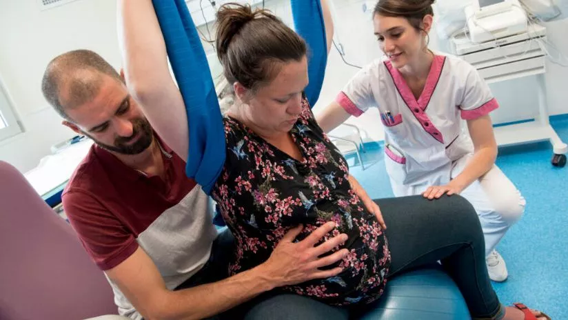 femme enceinte entrain de faire des exercices avec son mari et une soignante